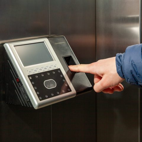 The man put his finger in the Fingerprint Access Control Terminal with face recognition function installed in the elevator of the business center, which tracks attendance in real time
